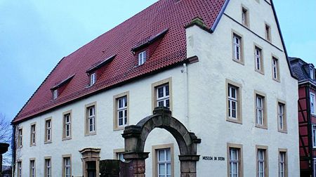 Historisches Gebäude mit rotem Dach und steinernem Torbogen, das Museum im "Stern" beherbergt.