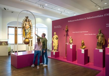 Ein Paar betrachtet Ausstellungsstücke in einem Museum zur Bildhauerkunst Südwestfalens.