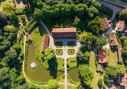 Luftaufnahme vom Kurpark Bad Holzhausen in Preußisch Oldendorf mit symmetrischen Gärten, Teich und zentralem Gebäude.