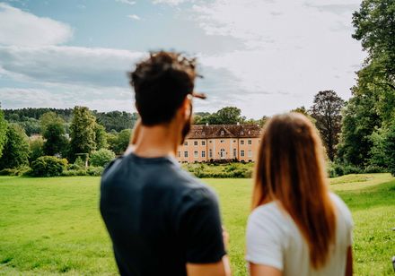 Zwei Personen blicken auf das Schloss Rheder in Brakel, Kulturland Kreis Höxter