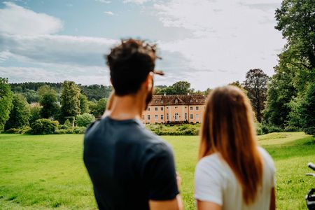 Zwei Personen blicken auf das Schloss Rheder in Brakel, Kulturland Kreis Höxter