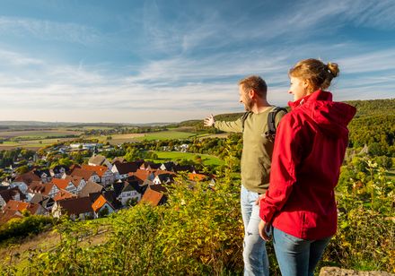 Ein Paar blickt von einem Hügel auf Schwalenberg und weite, von Feldern gesäumte Landschaften.