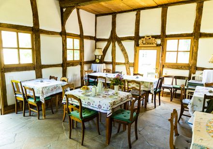 Gemütliches Interieur eines rustikalen Gastraums mit Holzbalken und gedeckten Tischen.