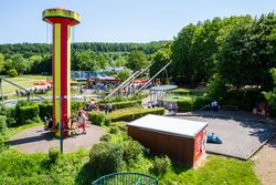 Hoch über der bunten Landschaft erhebt sich ein leuchtend gelber Aussichtsturm im Familien-Freizeitpark.