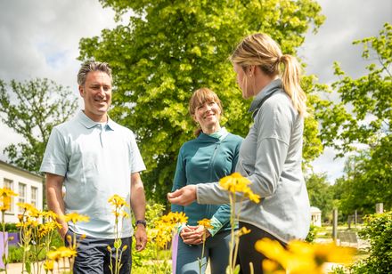 Drei Personen unterhalten sich im Kräutergarten