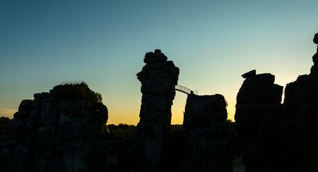 Felsformation Externsteine im Teutoburger Wald bei Sonnenuntergang, Silhouetten der Steine erkennbar.