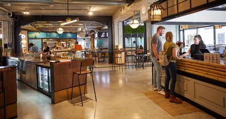 Ein modernes Café mit industriellem Ambiente, in dem Gäste an der Theke bestellen und genießen.