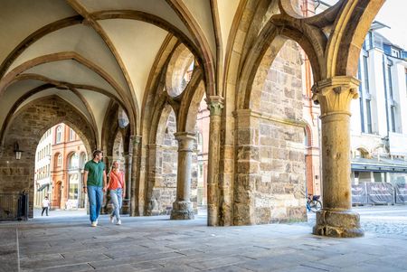 Zwei Personen gehen unter Torbögen / gewölbten Decken beim alten Rathaus in Minden