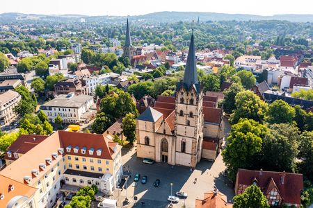 Luftbild der historischen Kirche in einer grünen Stadtlandschaft mit umliegenden Gebäuden und Straßen.