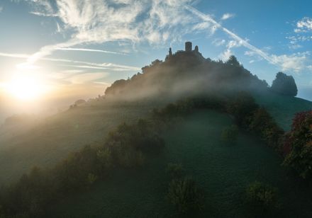 Desenberg mit Burgruine erscheint als Silhouette in der aufgehenden Sonne