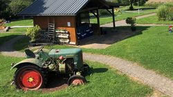 Garten mit Rasenfläche und grünem historischem Trecker