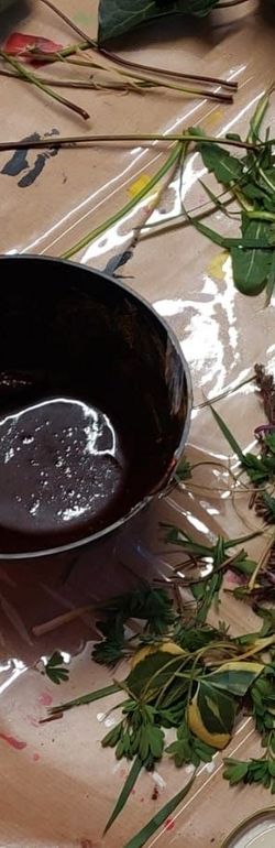 Künstlerische Materialien und natürliche Elemente wie Blätter und Pigmente auf einem Arbeitstisch verteilt.