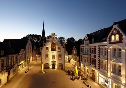 Der Marktplatz von Brakel bei Dämmerung, mit erleuchteten historischen Gebäuden und architektonischen Details.