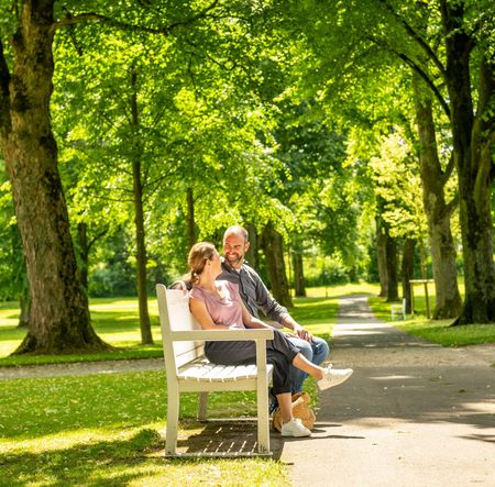 Zwei Personen auf einer weißen Bank im Gräflichen Park Bad Driburg