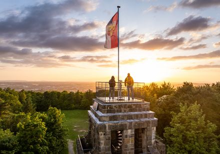 Bismarckturm in Herford bei Sonnenuntergang, zwei Personen genießen die Aussicht auf den Teutoburger Wald.