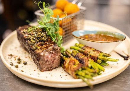 Teller mit Fleisch, Bohnen in Speck, Sauce und Beilage