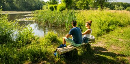 Pärchen sitzt am grünen Ufer eines Badesees