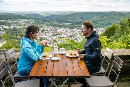 Eine Frau und ein Mann genießen Kaffee und Gebäck an einem Tisch mit Blick auf Bad Driburg.