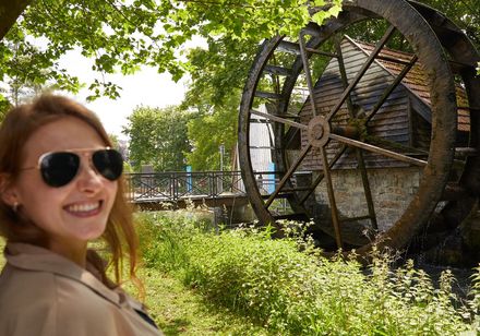 Frau mit Sonnenbrille, im Hintergrund Mühlrad