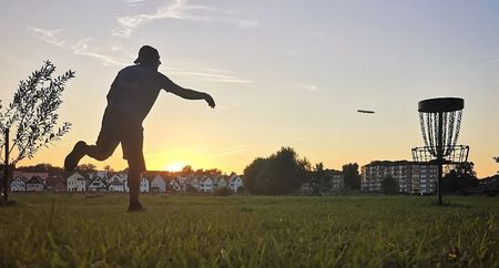 Person beim Disc Golf spielen bei Sonnenuntergang auf Kanzlers Weide in Minden