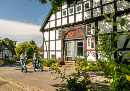 Zwei Radfahrer neben einem Fachwerkhaus
