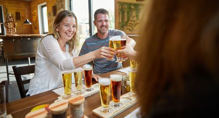 Eine fröhliche Gruppe beim Bierverkosten in einer Brauerei, mit Proben von verschiedenen Biersorten.