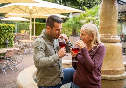 Zwei Personen mit Glas in der Hand vor einem Brunnen