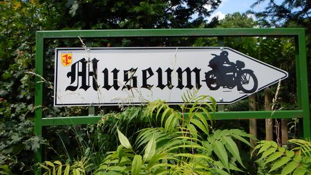 Blick auf ein Schild, das den Weg zum Motorradmuseum weist