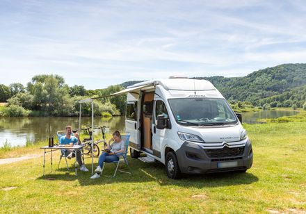 Campingvan mit Personen davor am Bootshaus Beverungen