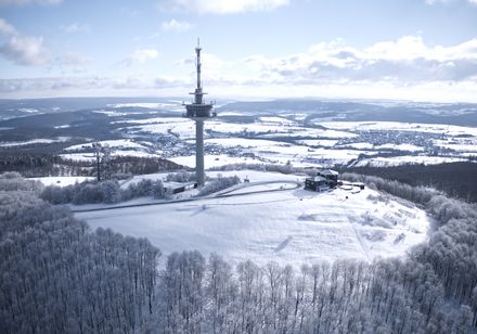 Verschneiter Köterberg mit Funkturm und weitläufiger Aussicht über bewaldete, schneebedeckte Hügel.
