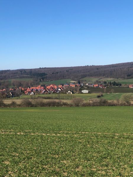 Blick auf ein Feld und ein Dorf in der Ferne