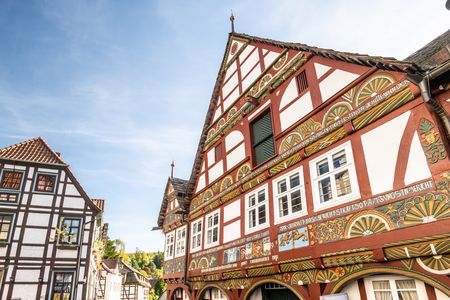 Historische Fachwerkhäuser mit reich verzierten Fassaden und klarer blauer Himmel im Hintergrund.