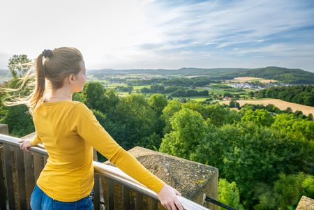 Frau blickt in die Landschaft von Borgholzhausen auf dem Turm der Burg Ravensberg
