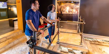 Zwei Personen erkunden ein interaktives Archäologie-Exponat in einem modernen Ausstellungsraum.
