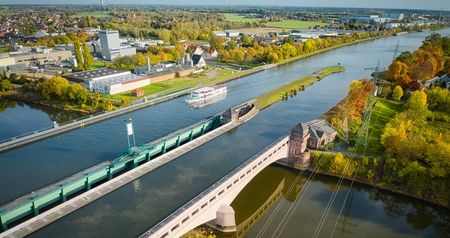 Das Bild zeigt das Wasserstraßenkreuz von oben. Auf dem Mittellandkanal fährt ein Schiff der Mindener Fahrgastschiffahrt.