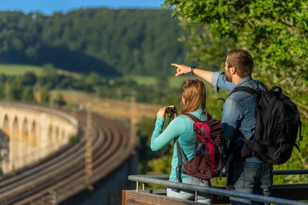 Ein Mann und eine Frau schauen mit dem Fernglas auf die Schienen des Viadukts in Altenbeken