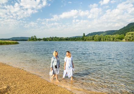 Zwei Frauen gehen durch das flache Wasser am Strand des Godelheimer Sees