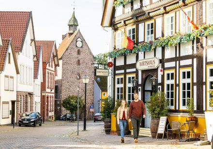 <p>Ein Paar spaziert eine malerische Altstadtstraße entlang, gesäumt von Fachwerkhäusern.</p>