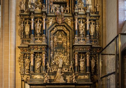 Ein kunstvoll verzierter, mehrstöckiger Altar mit zahlreichen religiösen Figuren in einer Kirche.