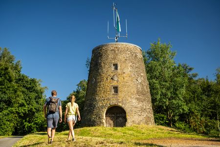 Kumsttonne Oerlinghausen: Zwei Personen gehen auf Windmühlenstumpf zu