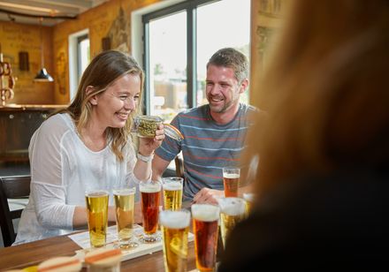 Lächelnde Menschen bei einer Bierverkostung in der Schaubrauerei von Rietberg, helle und einladende Atmosphäre.