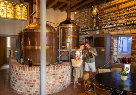 Nieheimer Biermuseum: Zwei Personen gucken eine Flasche an und stehen neben Kessel