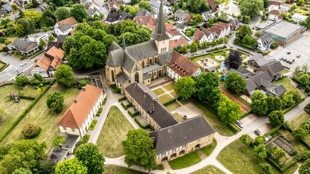 Luftaufnahme von Herzebrock-Clarholz mit Klosteranlage und Kirche, umgeben von Wohnhäusern und Grünflächen.