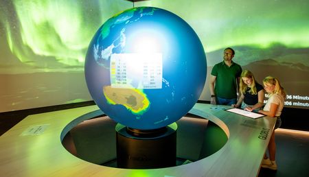 Familienausflug: Vater mit Kindern vor Weltkugel in der Klimaerlebniswelt Oerlinghausen