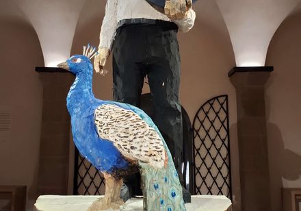 Holzfigur bestehend aus einem Mann mit Buch und einem Pfau, Paderborner Dom