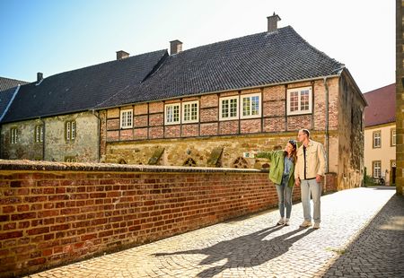 Paar läuft entlang Klosteranlage Herzebrock, Frau zeigt auf etwas