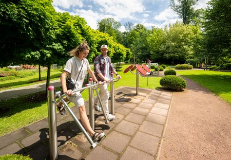 Zwei Personen machen Sportübungen an einem Gerät im Kurpark Bad Holzhausen (Preußisch Oldendorf)