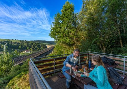Zwei Personen machen Picknick auf der Aussichtsplattform mit Blick auf das Viadukt in Altenbeken
