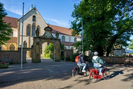 Zwei Radfahrer vor dem historischen Tor der Klosteranlage Cappenberg bei sonnigem Wetter.