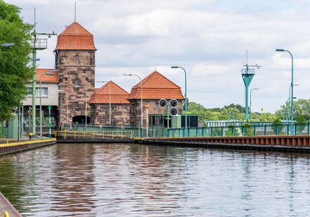 Schleuse in Minden mit historischem Backsteingebäude, Wasseroberfläche und grüner Umgebung.